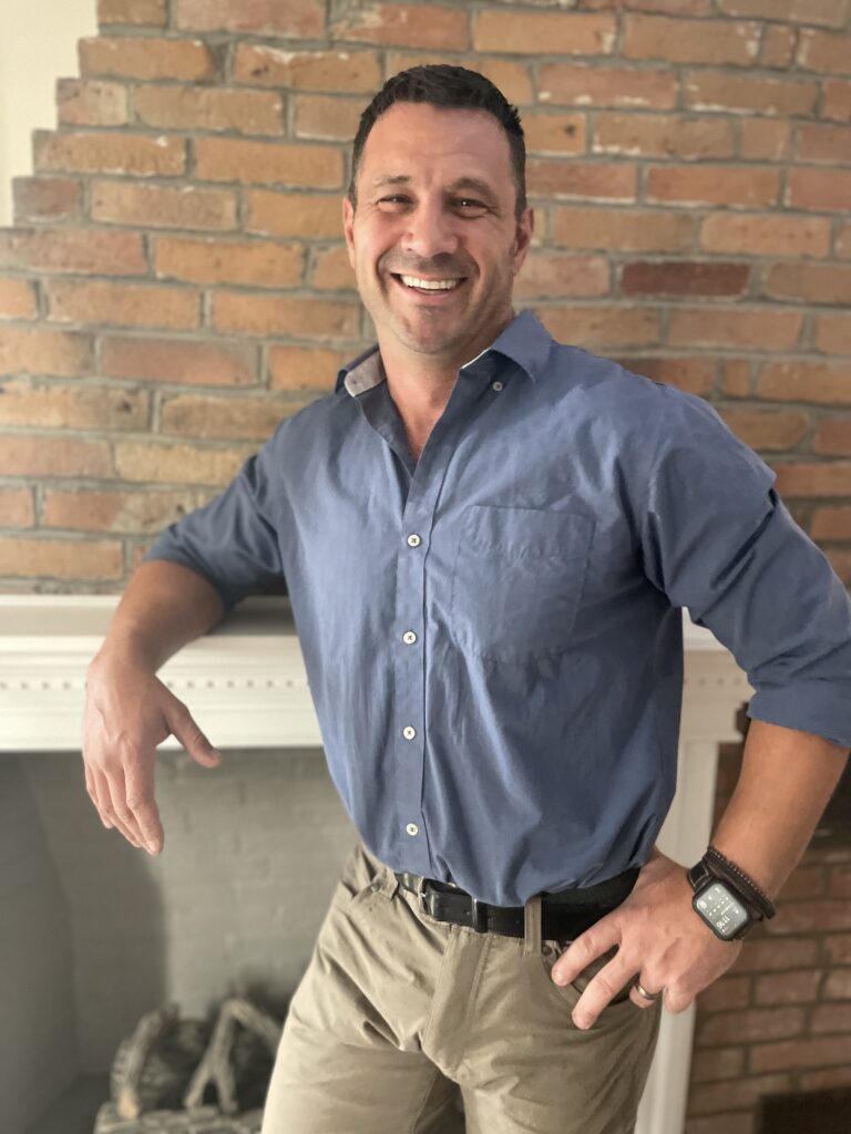 Image of Matt Ring smiling and standing by a mantle